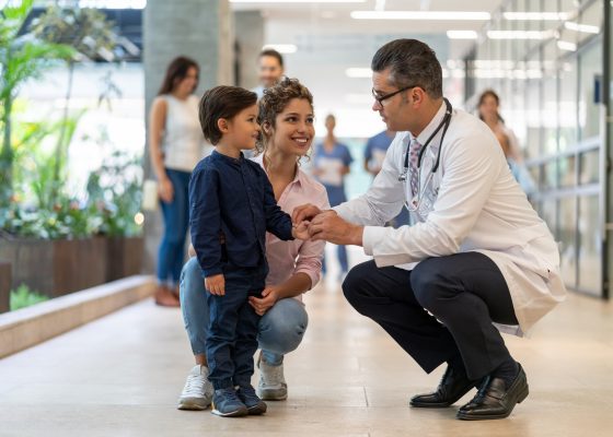 doctor tomandole la mano a un niño con su mamá