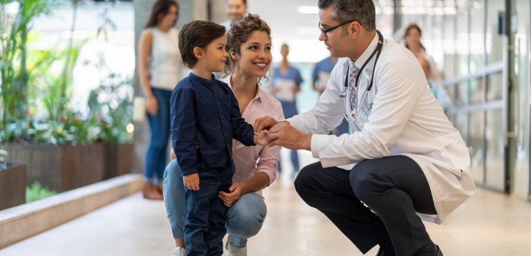 doctor tomandole la mano a un niño con su mamá