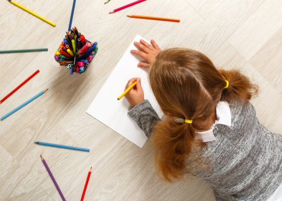 Niña coloreando una hoja en el suelo