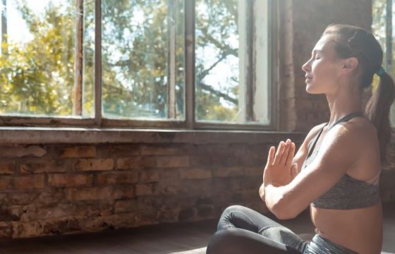 Mujer con las manos juntas en el pecho haciendo yoga