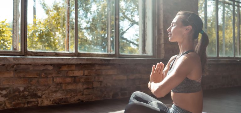 Mujer con las manos juntas en el pecho haciendo yoga