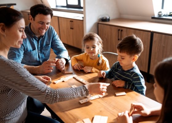 Familia compuesta de padres e hijos jugando dominós
