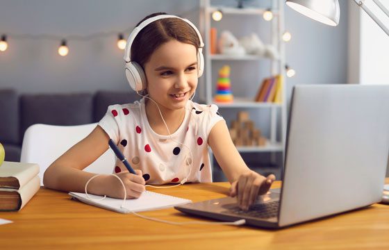 Niña con audífono estudiando en su computador